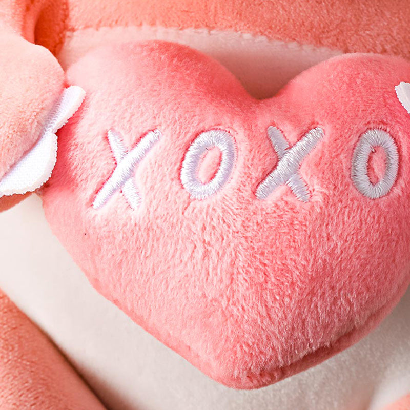 Draghetto rosa seduto con un cuscinetto a forma di cuore in mano e due cuoricini come narici della collezione Mini Family.